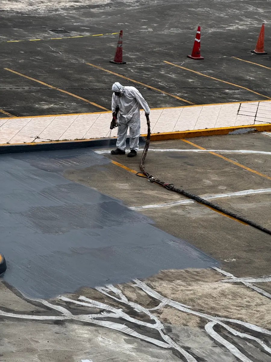 Aplicador con traje blanco y el rostro cubierto colocando la primera capa sobre la losa